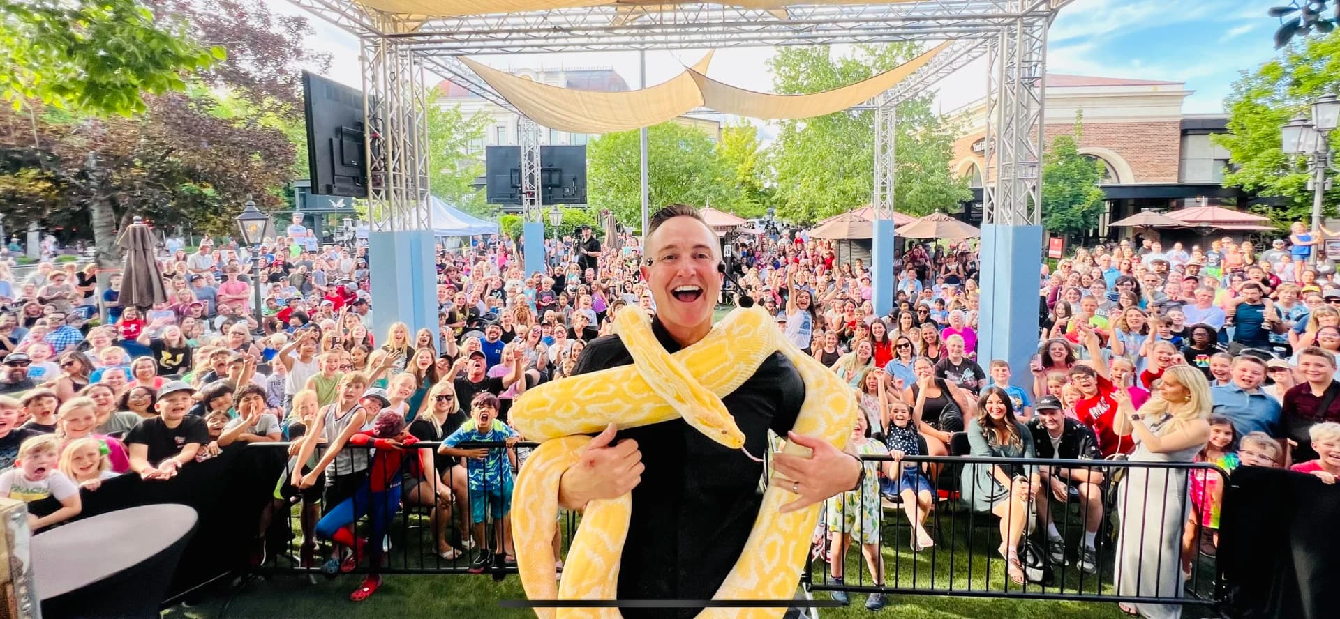 Corbin Maxey with snake around his neck in front of a crowd